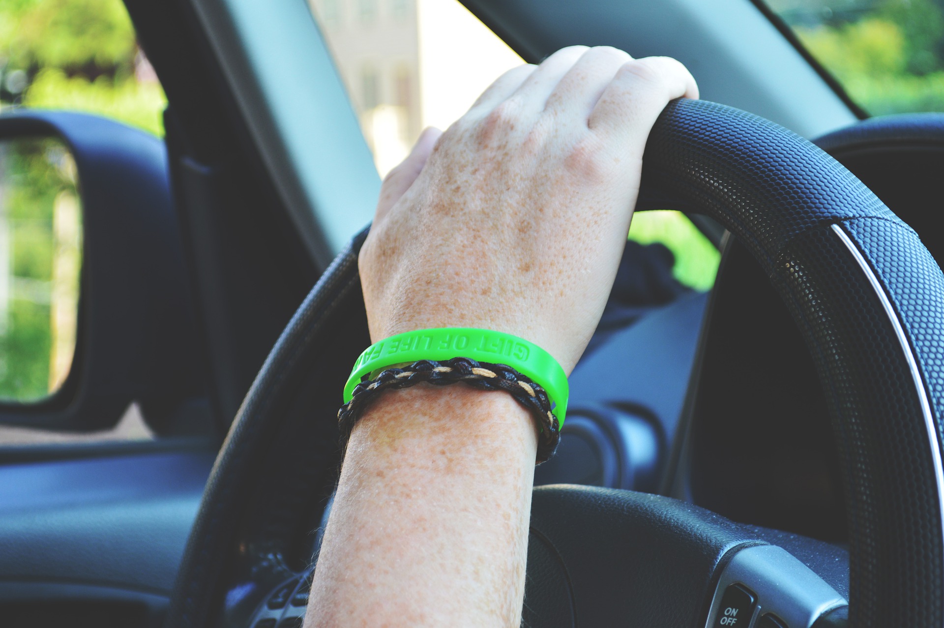 A person's hand on the steering wheel of a car